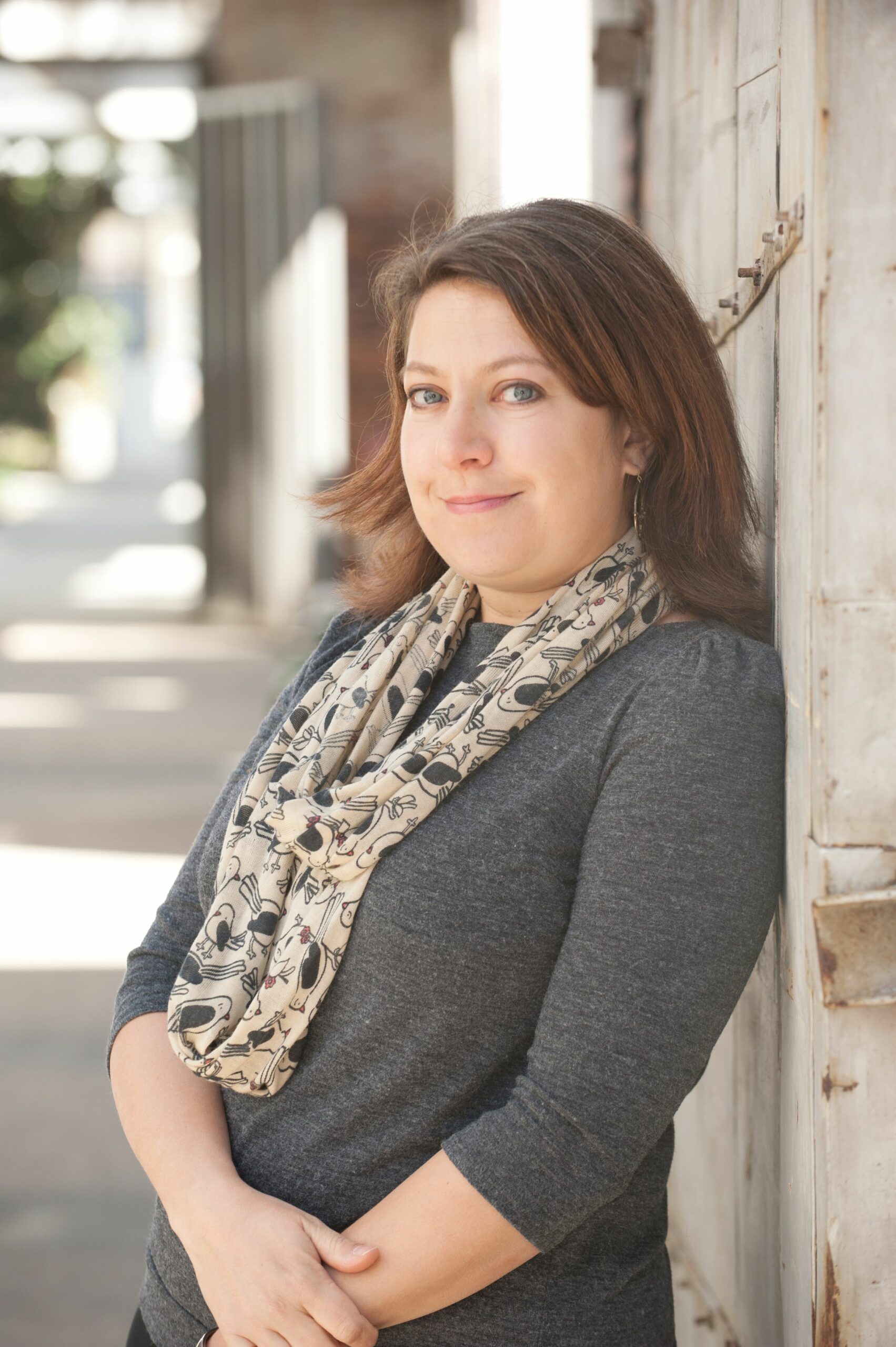 Writer Jessica Harlan leans against a brick wall.